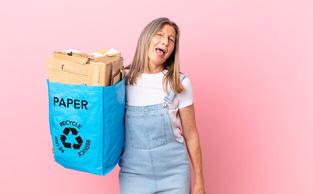 jolie femme d'âge moyen avec une attitude joyeuse et rebelle, plaisantant et tirant la langue du concept de carton de recyclage