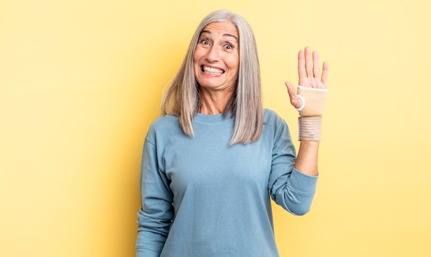 Jolie femme d'âge moyen ayant l'air heureuse et agréablement surprise. concept de bandage à la main