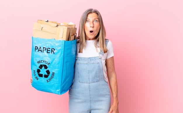 Jolie femme d'âge moyen ayant l'air très choquée ou surprise du concept de carton de recyclage