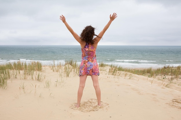 Jolie femme d'âge moyen debout dans l'océan avec ses bras levés