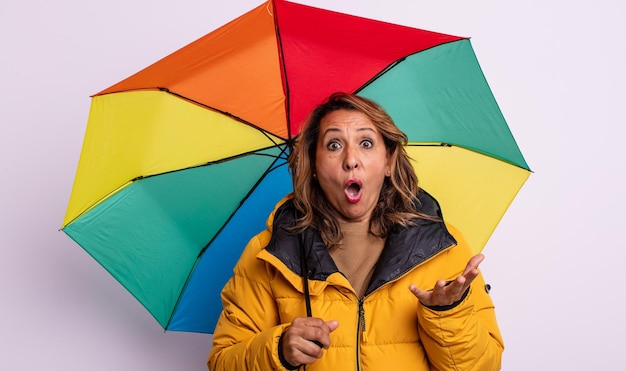 Jolie femme d'âge moyen émerveillée, choquée et étonnée d'une incroyable surprise. concept de parapluie