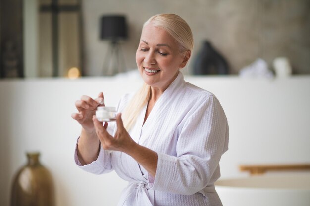 Photo jolie femme d'âge moyen avec un pot de crème pour le visage