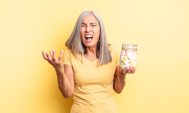 Jolie femme d'âge moyen qui a l'air en colère, agacée et frustrée. concept de bouteille de bonbons