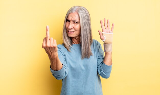 Jolie femme d'âge moyen se sentant en colère, agacée, rebelle et agressive. concept de bandage à la main