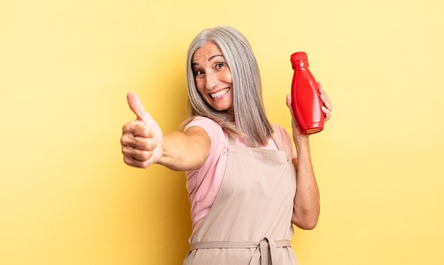 Jolie femme d'âge moyen se sentant fière de sourire positivement avec le concept de ketchup