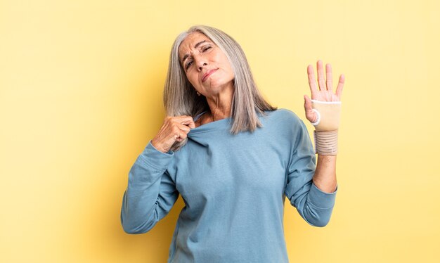 Jolie femme d'âge moyen se sentant stressée, anxieuse, fatiguée et frustrée. concept de bandage à la main