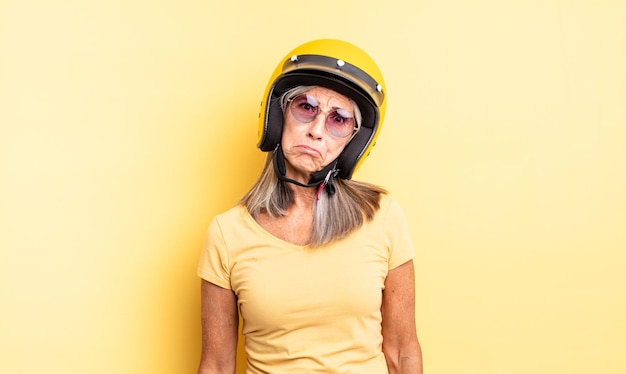 Jolie femme d'âge moyen se sentant triste et pleurnicharde avec un regard malheureux et pleurant. concept de casque de moto