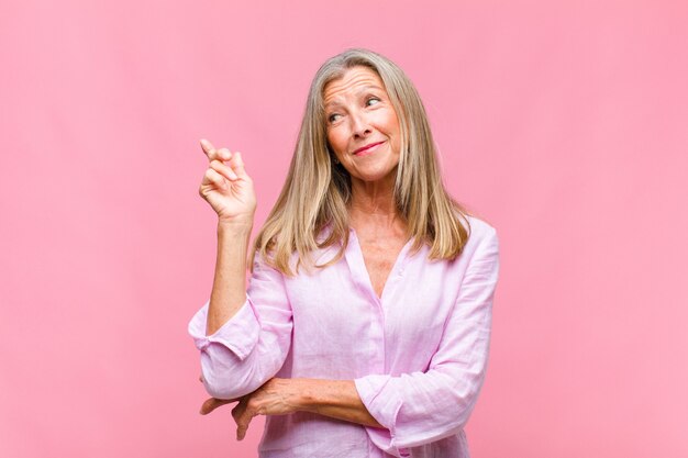 Jolie femme d'âge moyen souriant joyeusement et regardant de côté, se demandant, pensant ou ayant une idée