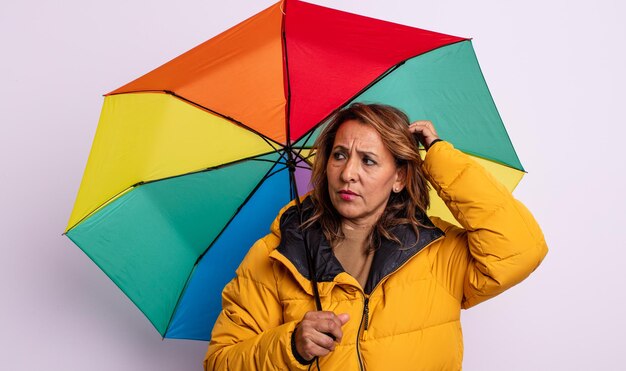 Jolie femme d'âge moyen souriant joyeusement et rêvant ou doutant. concept de parapluie