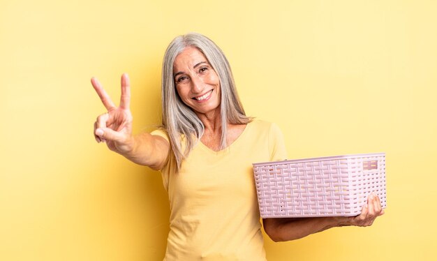 jolie femme d'âge moyen souriante et ayant l'air heureuse, gestant la victoire ou la paix. notion de panier vide