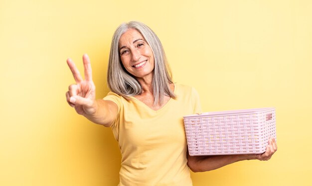 Jolie femme d'âge moyen souriante et semblant amicale, montrant le numéro deux. concept de panier vide