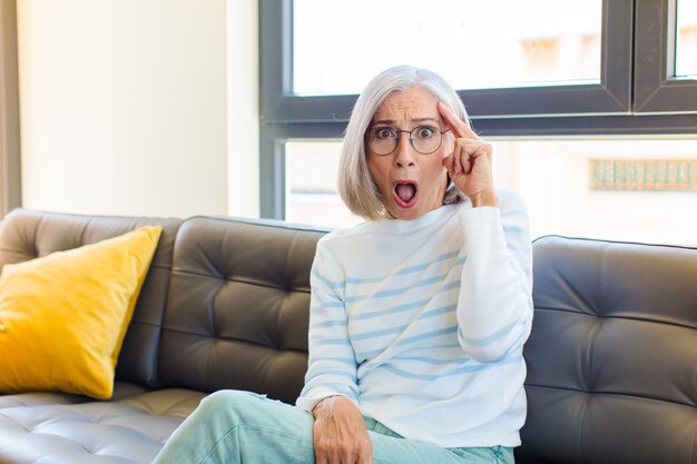 Jolie femme d'âge moyen à la surprise, la bouche ouverte, choquée, réalisant une nouvelle pensée