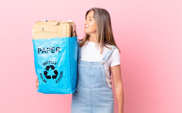 Jolie femme d'âge moyen sur la vue de profil pensant, imaginant ou rêvant le concept de recyclage de carton