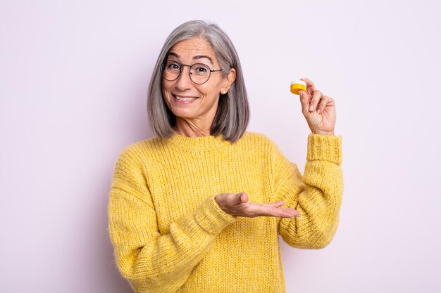 Jolie femme âgée souriante joyeusement, se sentant heureuse et montrant un concept. concept de lentilles de contact