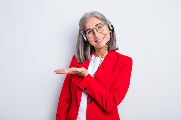 Jolie femme âgée souriante joyeusement, se sentant heureuse et montrant un concept. concept de télévendeur