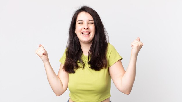 Jolie femme à l'air extrêmement heureuse et surprise de célébrer le succès en criant et en sautant