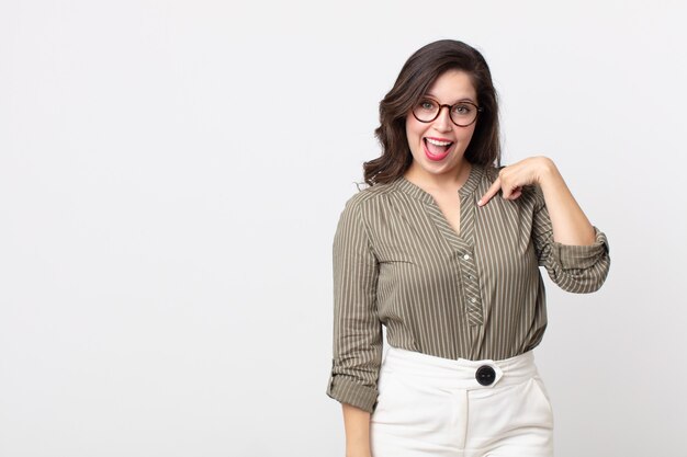 Jolie femme à l'air heureuse, fière et surprise, pointant joyeusement vers elle-même, se sentant confiante et élevée