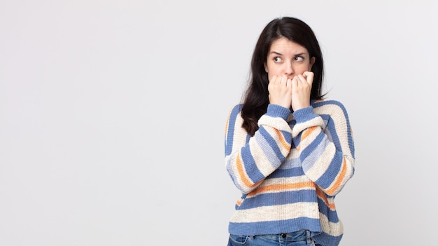 Jolie femme à l'air inquiète, anxieuse, stressée et effrayée, se rongeant les ongles et regardant vers l'espace de copie latéral