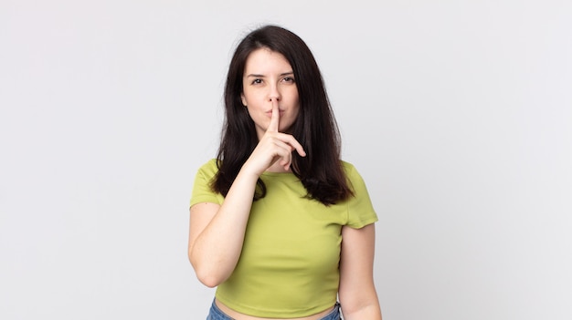 Jolie femme à l'air sérieuse et croisée avec le doigt pressé sur les lèvres exigeant le silence ou le silence, gardant un secret