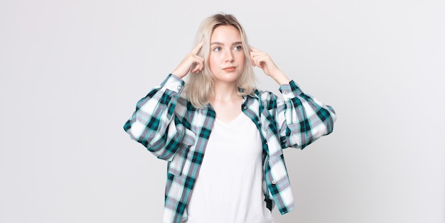 Jolie femme albinos se sentant confuse ou doutant, se concentrant sur une idée, réfléchissant fort, cherchant à copier l'espace sur le côté