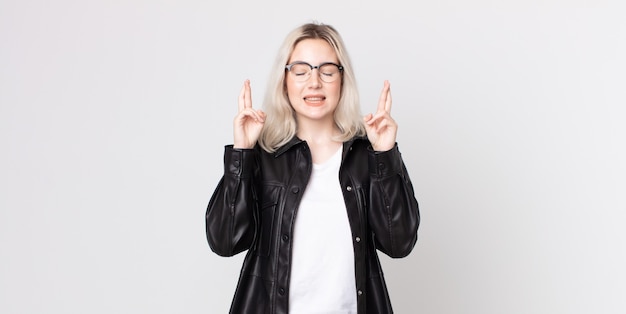 Jolie femme albinos se sentant nerveuse et pleine d'espoir, croisant les doigts, priant et espérant bonne chance