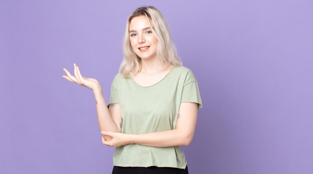 Jolie femme albinos souriante fièrement et avec confiance, se sentant heureuse et satisfaite et montrant un concept sur l'espace de copie