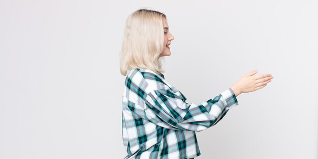 Photo jolie femme albinos souriante, vous saluant et offrant une poignée de main pour conclure un accord réussi, concept de coopération