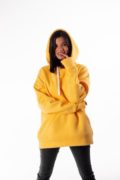 Jolie femme d'apparence latine porte un sweat à capuche jaune sur fond blanc La fille a l'air sexy et heureuse L'élégante brune porte un sweat-shirt brillant Vêtements Allseason