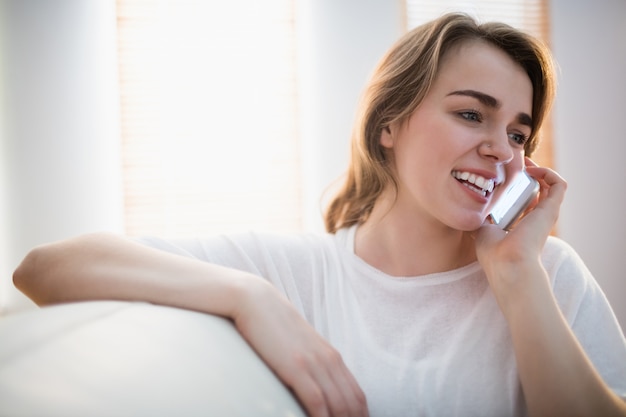 Jolie femme appelant au téléphone sur le canapé dans le salon