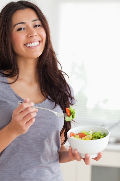 Jolie femme appréciant un bol de salade en se tenant debout