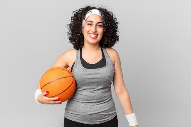 Jolie femme arabe ayant l'air heureuse et agréablement surprise et tenant un ballon de basket. notion de sport