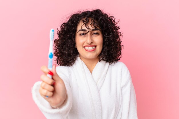 Jolie femme arabe portant un peignoir et utilisant une brosse à dents