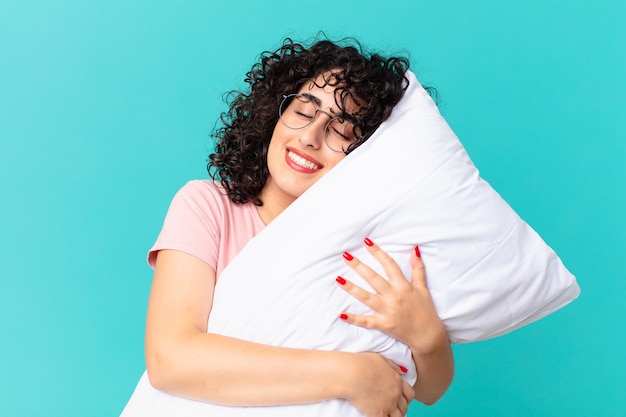 Jolie femme arabe en pyjama et avec un oreiller.