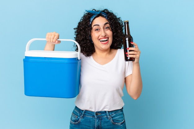 Jolie femme arabe avec un réfrigérateur portable et une bière