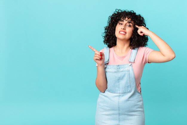 Jolie femme arabe se sentant confuse et perplexe, vous montrant que vous êtes fou