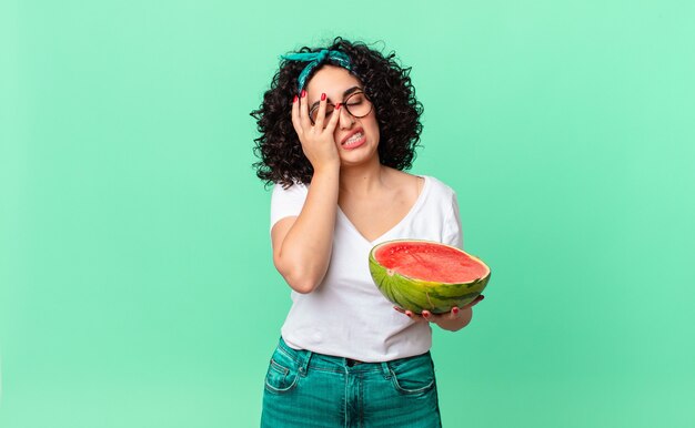 Jolie femme arabe se sentant ennuyée, frustrée et endormie après une fatigue et tenant une pastèque. concept d'été