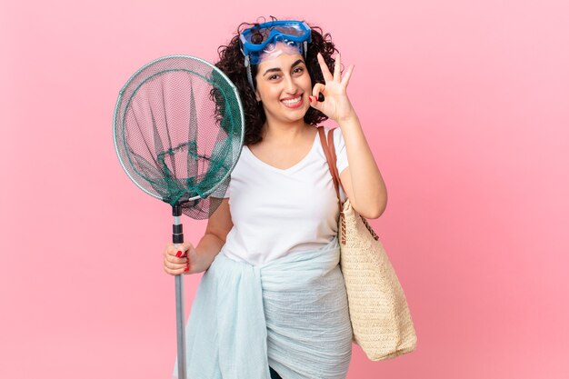 Jolie femme arabe se sentant heureuse, montrant son approbation avec un geste correct avec des lunettes. concept de pêcheur