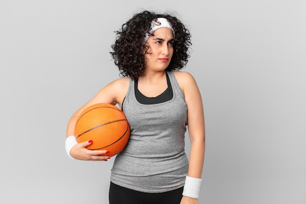 Jolie femme arabe se sentant triste, bouleversée ou en colère et regardant sur le côté et tenant un ballon de basket. notion de sport