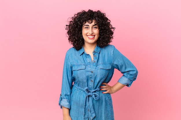 jolie femme arabe souriant joyeusement avec une main sur la hanche et confiante