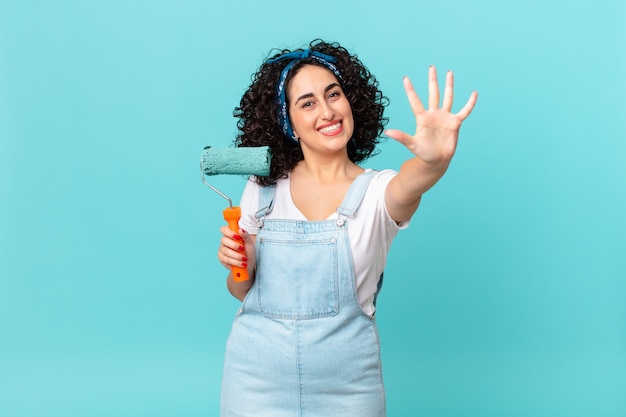 Jolie femme arabe souriante et semblant amicale, montrant le numéro cinq. concept de maison de peinture