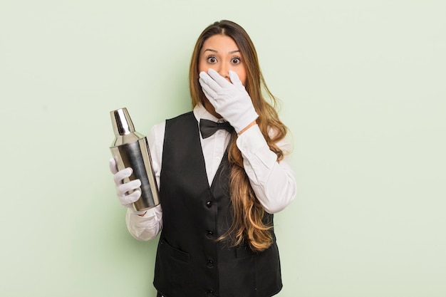 Jolie femme asiatique couvrant la bouche avec les mains avec un choc. barman avec un shaker