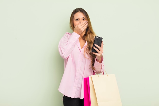 Jolie femme asiatique couvrant la bouche avec les mains avec un concept de sacs à provisions choqué