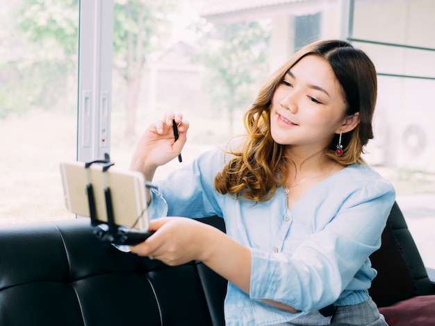 Jolie femme asiatique est le blogueur en ligne pour examiner le produit