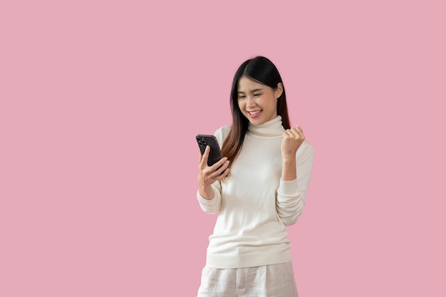 Une jolie femme asiatique lève la main de joie en recevant de bonnes nouvelles par SMS