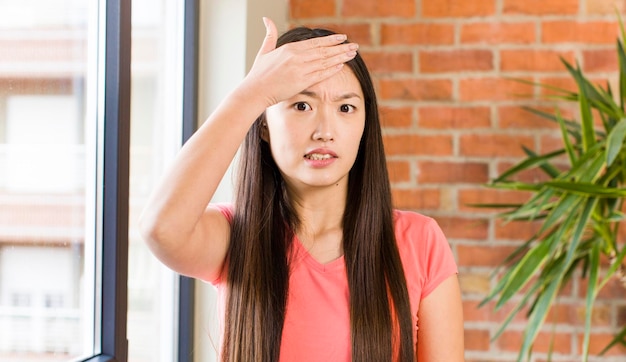 Jolie femme asiatique à la maison contre le mur de briques avec une plante