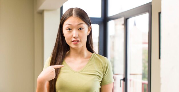 Jolie femme asiatique à la maison avec fond de grandes fenêtres