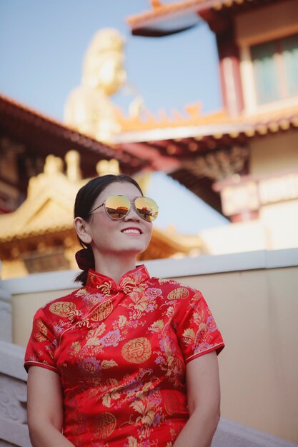 Jolie femme asiatique portant un costume chinois rouge debout en plein air