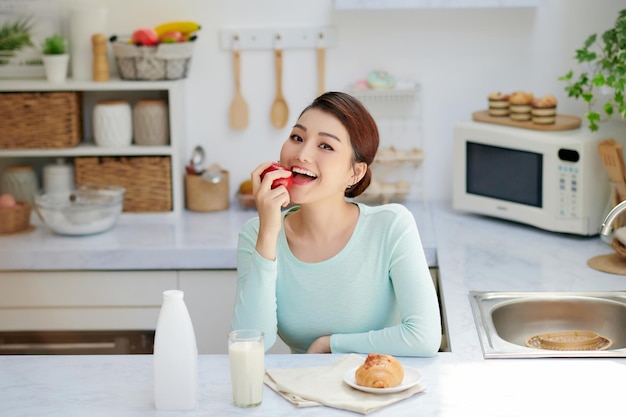 Jolie femme asiatique prenant son petit déjeuner et buvant du lait à la maison