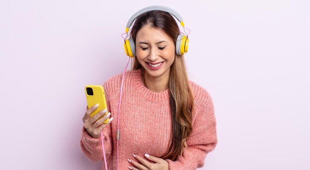 Jolie femme asiatique riant aux éclats d'une blague hilarante. casque et concept de téléphone