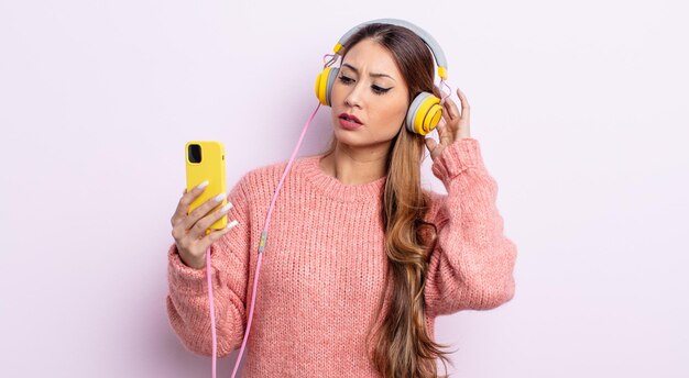 Jolie femme asiatique se sentant perplexe et confuse, se grattant la tête. casque et concept de téléphone